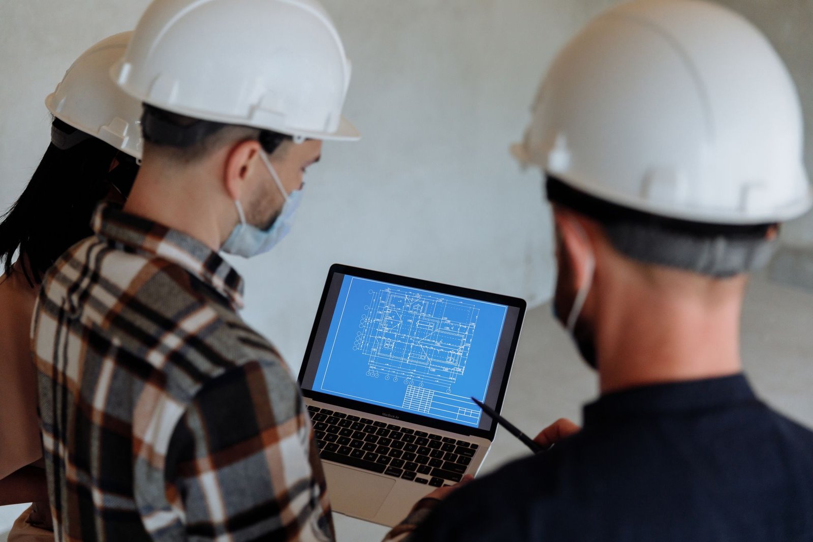Technical team reviewing drawings on a laptop at a construction site